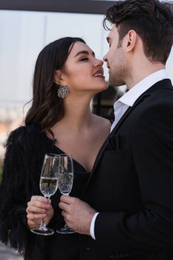 Adam ve mutlu kadın şampanya kadehlerini tokuşturuyor 