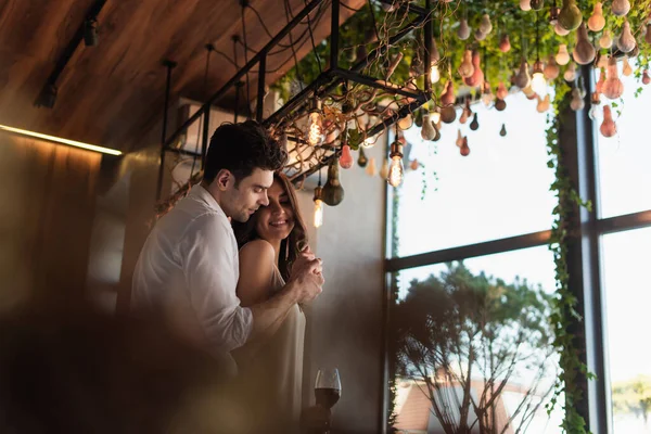 Cheerful Man Hugging Happy Girlfriend Slip Dress Restaurant — Stockfoto