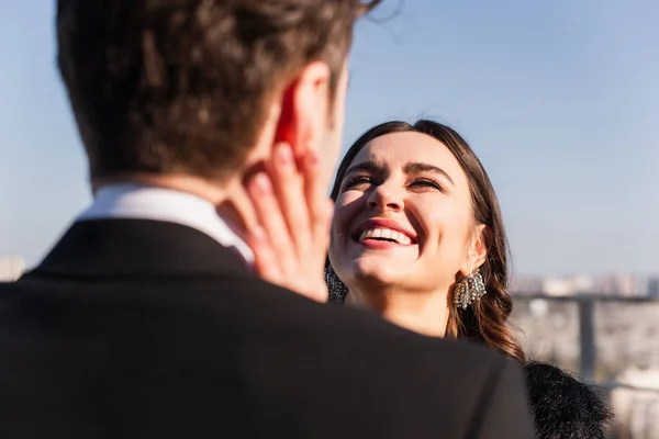 joyful woman touching face of blurred boyfriend