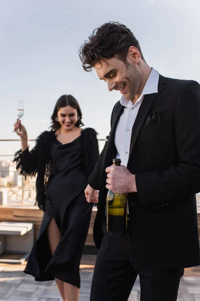 Happy Man Bottle Champagne Holding Hand Blurred Cheerful Girlfriend — Stock Photo, Image