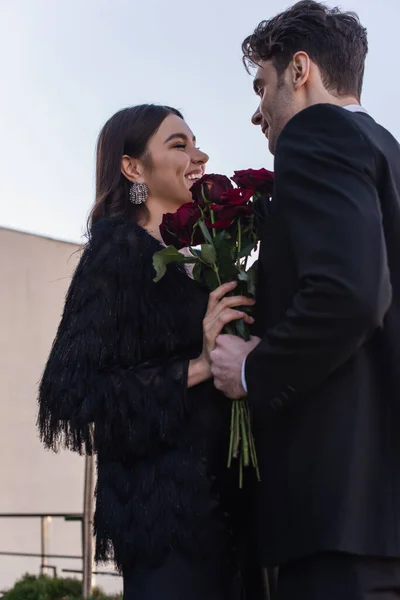 幸せな女性の近くに赤いバラを持つ男の毛皮のジャケット — ストック写真