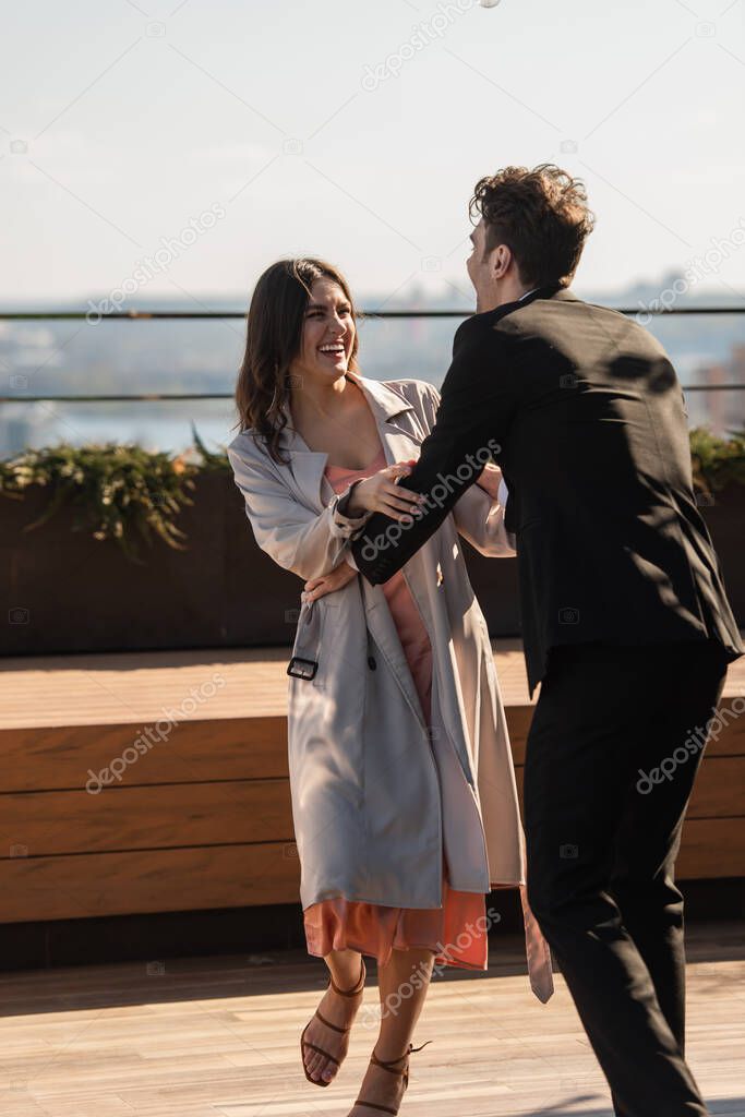 cheerful man and happy woman looking at each other on terrace of restaurant 