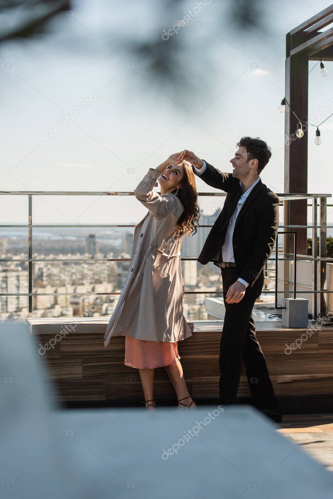 happy couple holding hands while dancing on roof