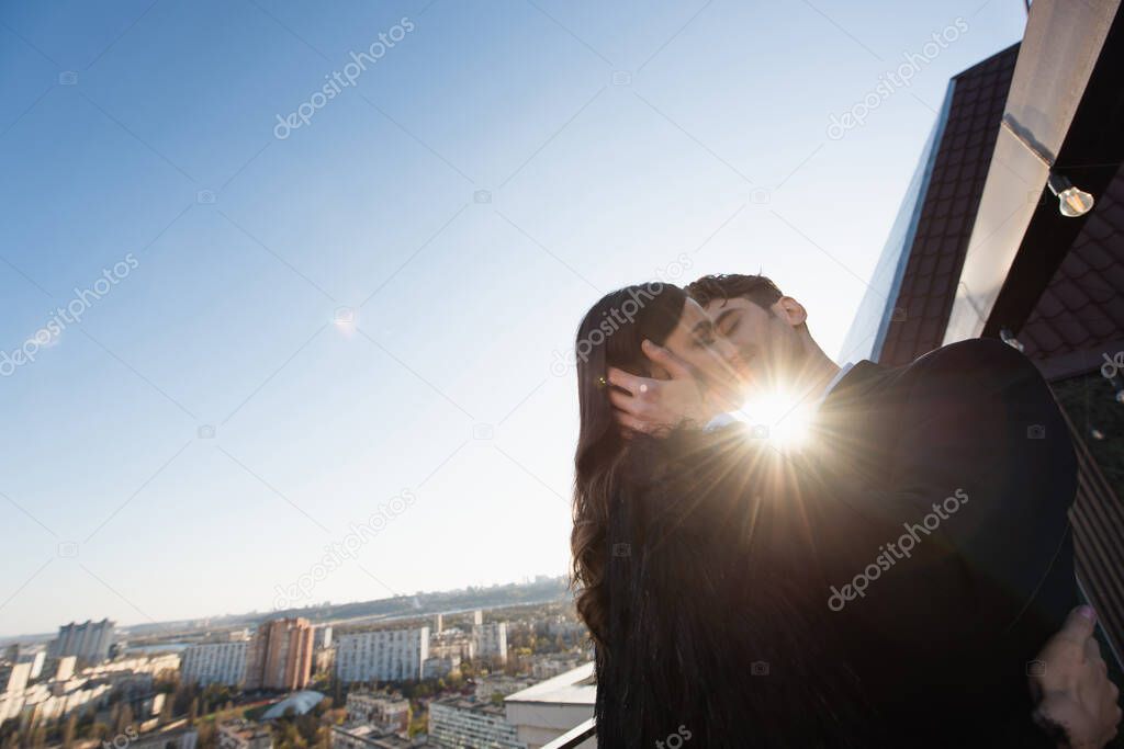 woman in faux fur jacket kissing with man on roof