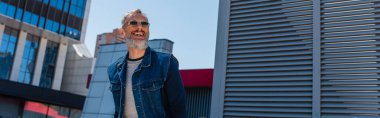 joyful middle aged man in sunglasses on urban street, banner