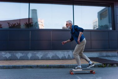 side view of mature man riding longboard on urban street