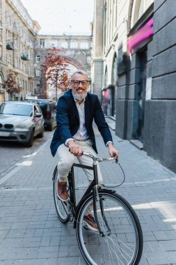 smiling man listening music in earphones and riding bicycle 