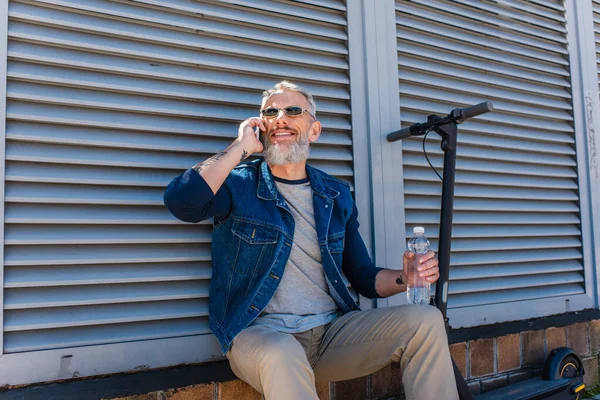Cheerful Mature Man Sunglasses Talking Smartphone Holding Bottle Water Scooter — Stock Photo, Image