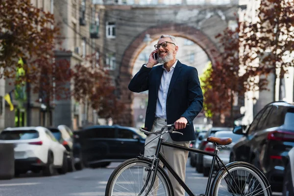 Joyful Middle Aged Man Blazer Glasses Talking Smartphone Standing Bicycle — Zdjęcie stockowe