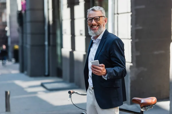 Happy Middle Aged Man Blazer Glasses Holding Smartphone Standing Bicycle — Zdjęcie stockowe