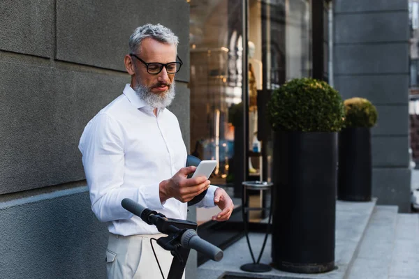Mature Man Shirt Glasses Holding Helmet Using Smartphone Electric Scooter — Stockfoto