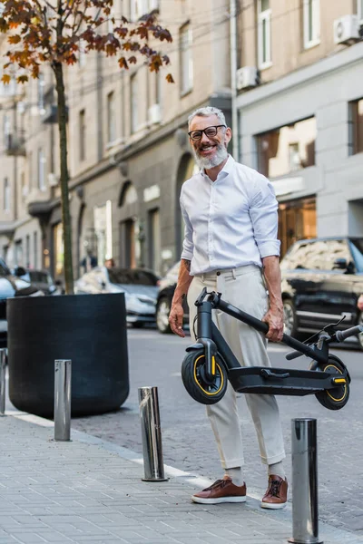 Smiling Middle Aged Man White Shirt Carrying Electric Scooter Street — Zdjęcie stockowe