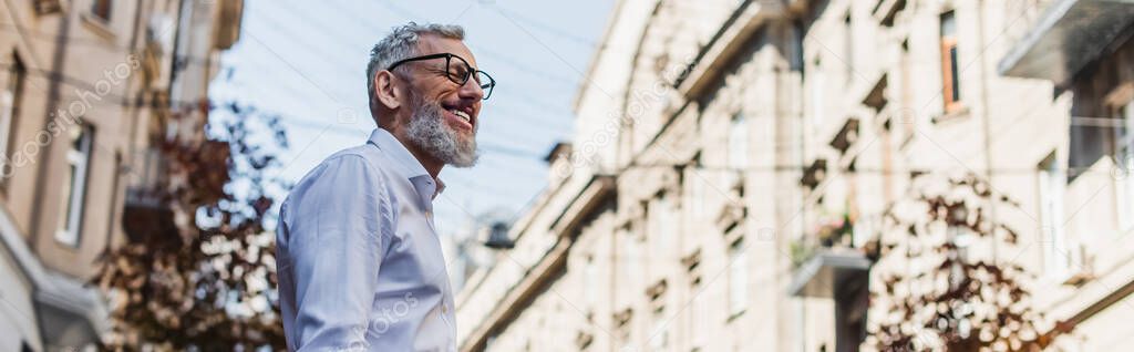 low angle view of smiling middle aged man in white shirt on street, banner