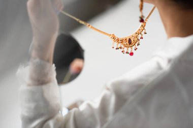 Beyaz kolye tutan genç gelinin kırpılmış görüntüsü