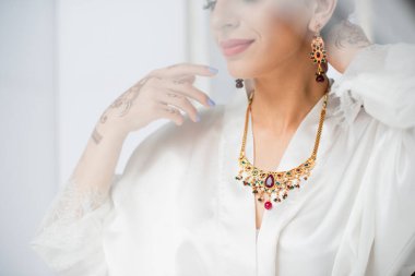 partial view of young indian bride wearing necklace on white clipart