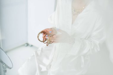 cropped view of young indian bride holding bracelets near mirror  clipart
