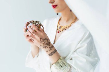 cropped view of young indian bride holding bracelets on white  clipart