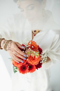 Genç Hintli gelin ve mehndi beyaz üzerinde çiçekler tutuyor.