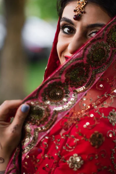 赤サリの陽気で若いインドの花嫁飾りでスカーフを調整 — ストック写真