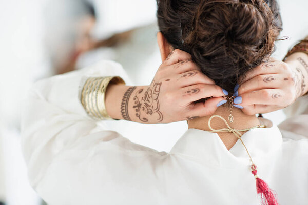 back view of indian bride with mehndi on hands wearing necklace 