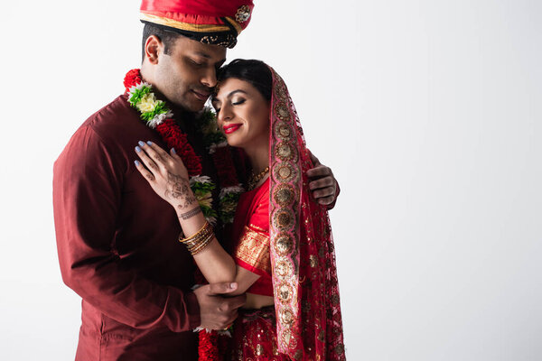 happy indian couple of husband and wife in traditional clothing hugging isolated on grey 