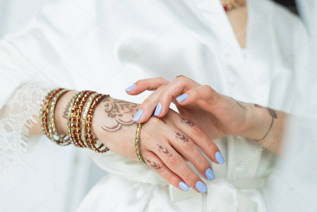 cropped view of indian bride with mehndi on hands wearing bracelets 