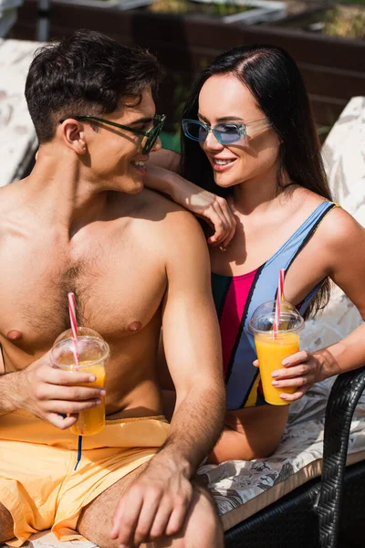 Lächelnder Mann Badehose Schaut Freundin Mit Orangensaft Auf Liegestuhl — Stockfoto