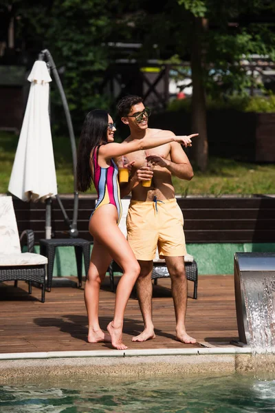 Cheerful Woman Swimsuit Pointing Finger Boyfriend Swimming Pool — Stock Photo, Image