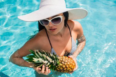 Güneş şapkalı kadının bilardoda olgun ananas tutuşu. 