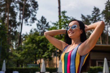 Young woman in swimsuit smiling with closed eyes outdoors  clipart