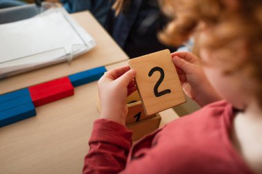 İki numaralı ahşap kartı tutan bulanık çocuk görüntüsü.
