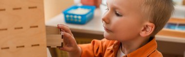 Çocuk Montessori okulunda öğrenim sırasında tahta kutuda sancak açıyor.