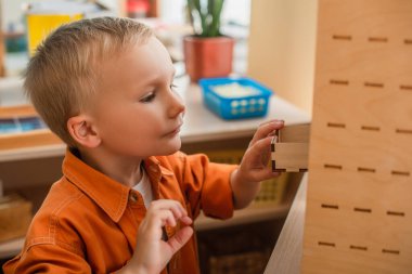 Çocuk Montessori okulunda bilişsel oyun oynarken ahşap kutuda dolap açıyor.