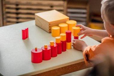 Montessori okulunda kırmızı ve sarı bloklarla oynayan çocuğun kısmi görüntüsü
