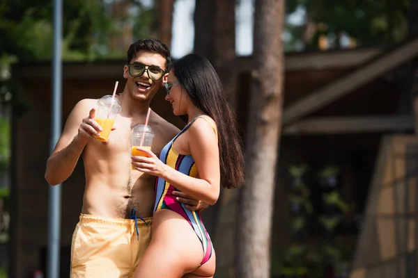 Hombre Sin Camisa Con Zumo Naranja Abrazando Novia Señalando Con — Foto de Stock