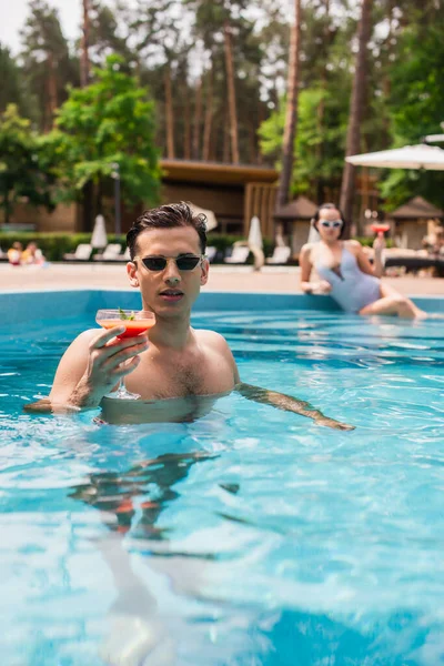 Man Sunglasses Holding Cocktail Swimming Pool Blurred Girlfriend — Stock Photo, Image