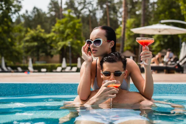 Young Man Drinking Cocktail Girlfriend Adjusting Sunglasses Pool — Stock Photo, Image