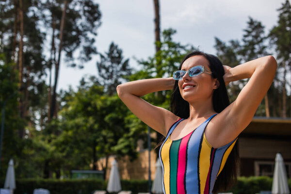 Young woman in swimsuit smiling with closed eyes outdoors 