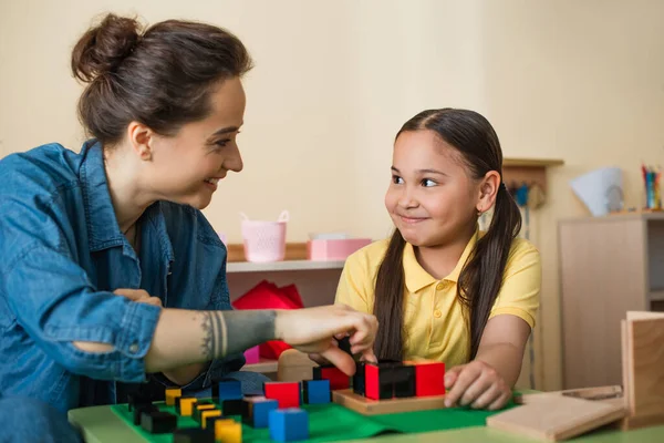 Счастливая Девочка Молодая Учительница Смотрят Друг Друга Играя Деревянными Кубиками — стоковое фото
