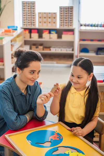 Młody Nauczyciel Dając Kawałek Układanki Azjatyckiej Dziewczyny Szkole Montessori — Zdjęcie stockowe