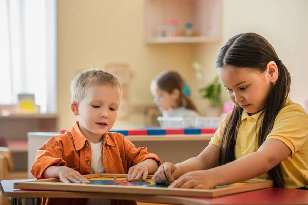 Wielonarodowe Dzieci Łączące Puzzle Mapy Świata Pobliżu Dziewczyny Rozmazanym Tle — Zdjęcie stockowe