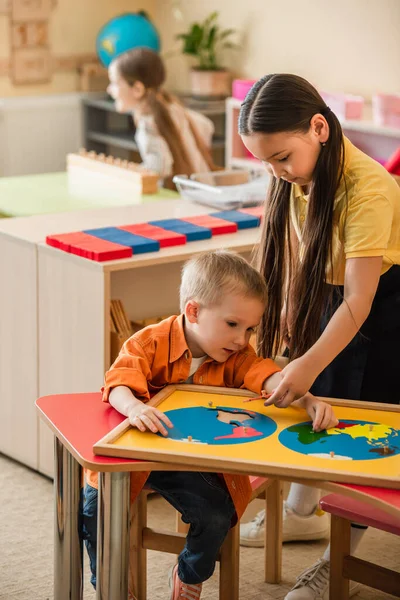 Asiatico Ragazza Aiutare Ragazzo Combinando Mondo Mappa Puzzle Montessori Scuola — Foto Stock