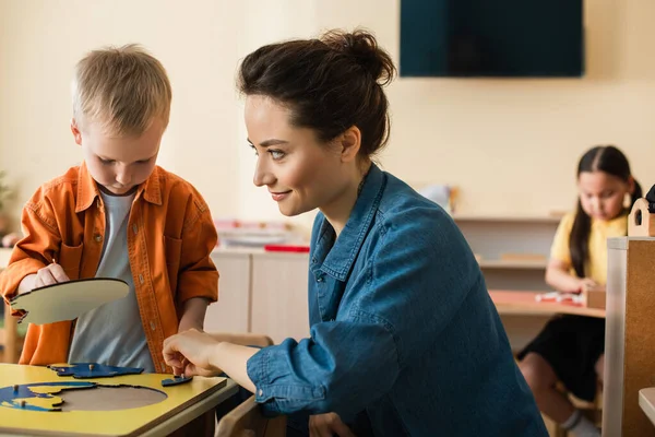 Glimlachende Leraar Kijken Naar Jongen Combineren Aarde Kaart Puzzel Buurt — Stockfoto