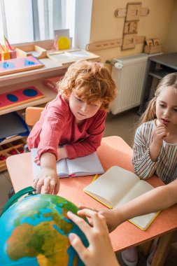 Çocuklar Montessori okulunda ders sırasında dünyaya bakıyorlar.