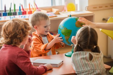 Bulanık öğretmen ve Montessori okulundaki çocukların yanına bakan hayrete düşmüş çocuk.