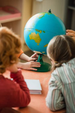 Montessori okulunda dünyanın yakınındaki bulanık çocukların arka görüntüsü