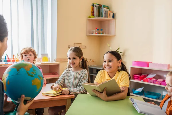 Glückliche Multiethnische Kinder Schauen Auf Lehrer Der Globus Klassenzimmer Hält — Stockfoto