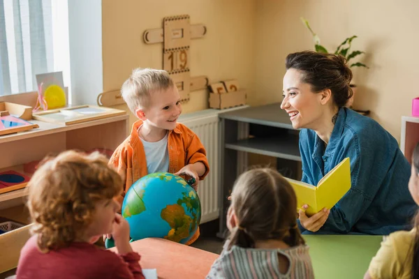 Felice Ragazzo Tenendo Globo Vicino Sorridente Insegnante Bambini Multietnici — Foto Stock