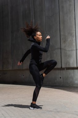 Kentsel caddede ısınan Afro-Amerikan sporcu kadının yan görüntüsü 