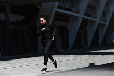 Kentsel caddede kulaklık eğitimi alan Afrikalı Amerikalı bir koşucu 